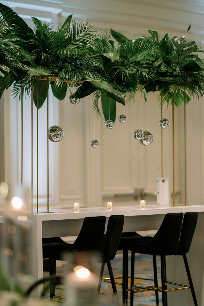 Overhead greenery installation with hanging mirror balls
